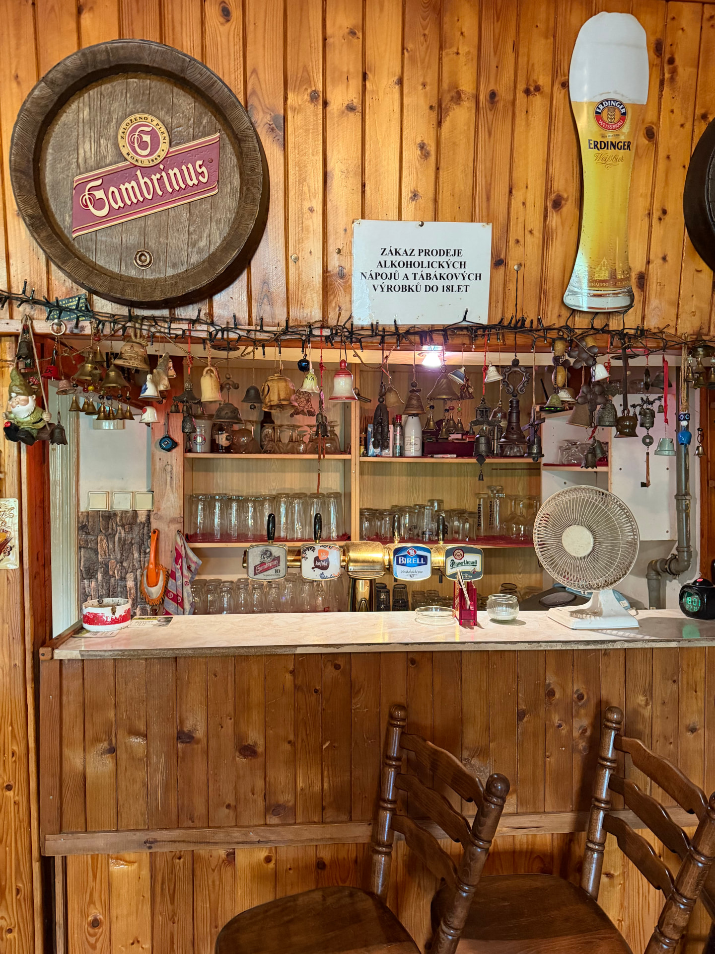 Dřevěný bar s pivními výčepy a kolekcí zvonků